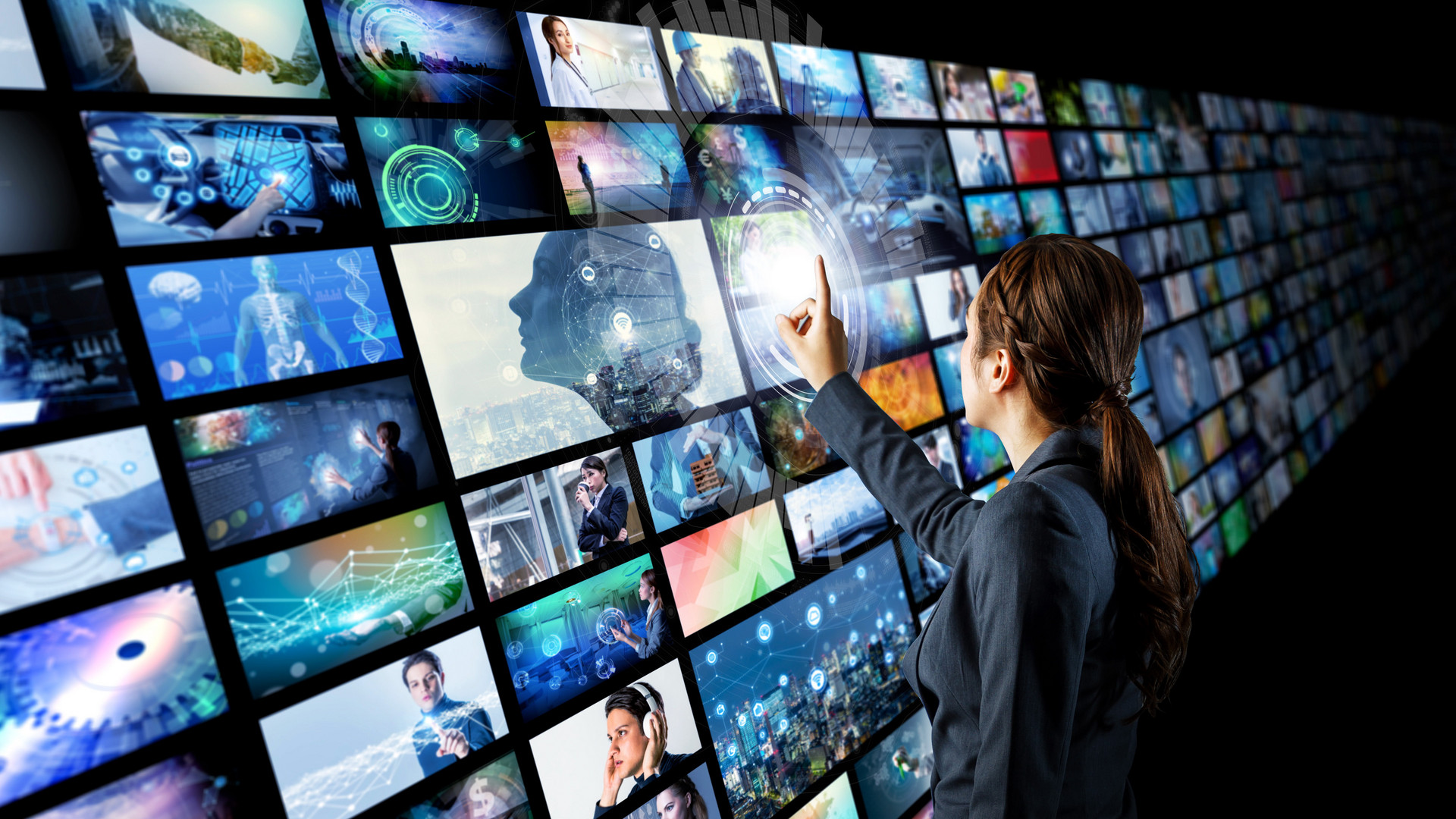 Frau vor Bildschirmwand mit zahlreichen unterschiedlichen Sender-Angeboten